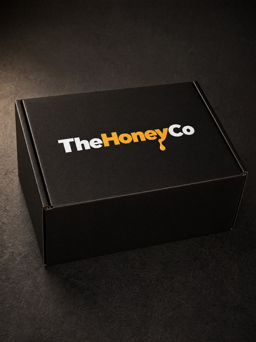 A closed black TheHoneyCo box on a dark stone surface